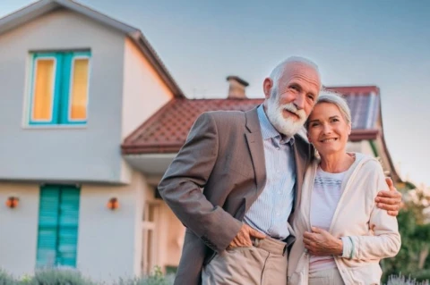 Couple senior devant leur maison